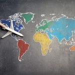 A person’s hand holding an airplane toy on a world map
