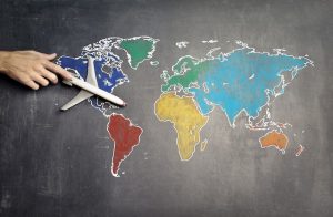 A person’s hand holding an airplane toy on a world map
