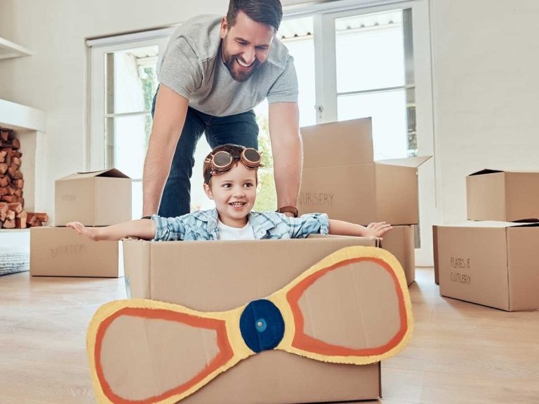 Dad Pushing handmade box airplane with kid inside to celebrate international move