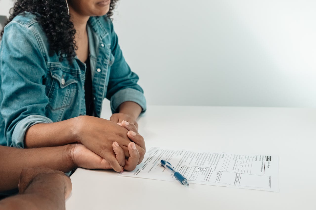 A couple holding hands while a white paper is on the desk in front of them