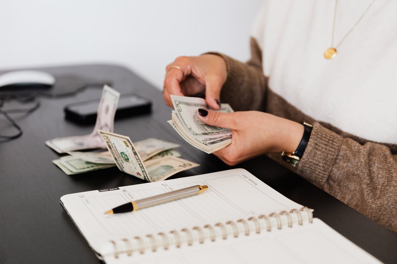 Woman counting cash next to a notebook